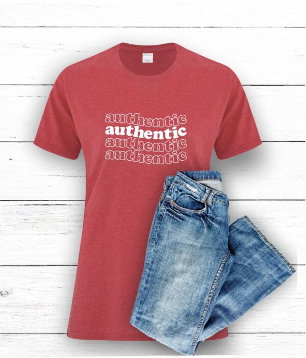 women's cotton polyester blend red heather t-shirt with white authentic graphic text on the front with a pair of jeans on a white wood background